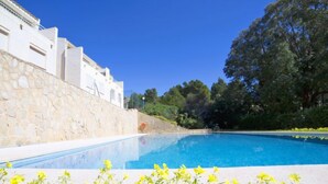 A swimming pool with clear blue water, surrounded by a stone wall and lush greenery. - Bernia Golf by Interhome (Altea)