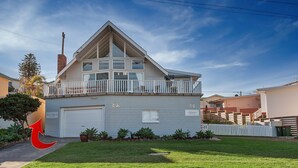 A two-story house with a balcony, a garage, and a well-maintained lawn. - Little Kingsley Beach House - Back Flat - across the road from the Beach (Boat Harbour)