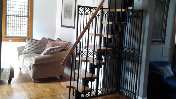 A staircase with a wooden handrail and black metal railings, leading to an upper floor. - Riverfront rental (South Elgin)