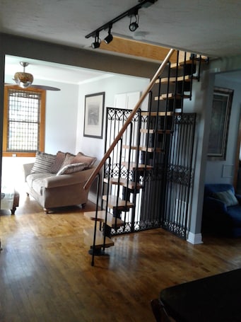 A staircase with a wooden handrail and black metal railings, leading to an upper floor.