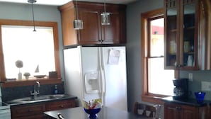 A kitchen with wooden cabinets, a white refrigerator, a dining table with chairs, and pendant lights. - Riverfront rental (South Elgin)