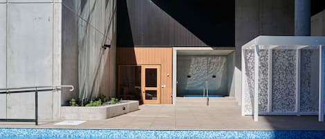 A modern pool area with a clear view of the pool, a wooden door, and a white structure with a lattice design.
