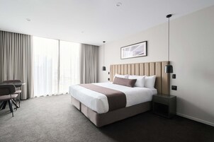 Una habitación de hotel moderna con una cama grande, un escritorio y una silla.