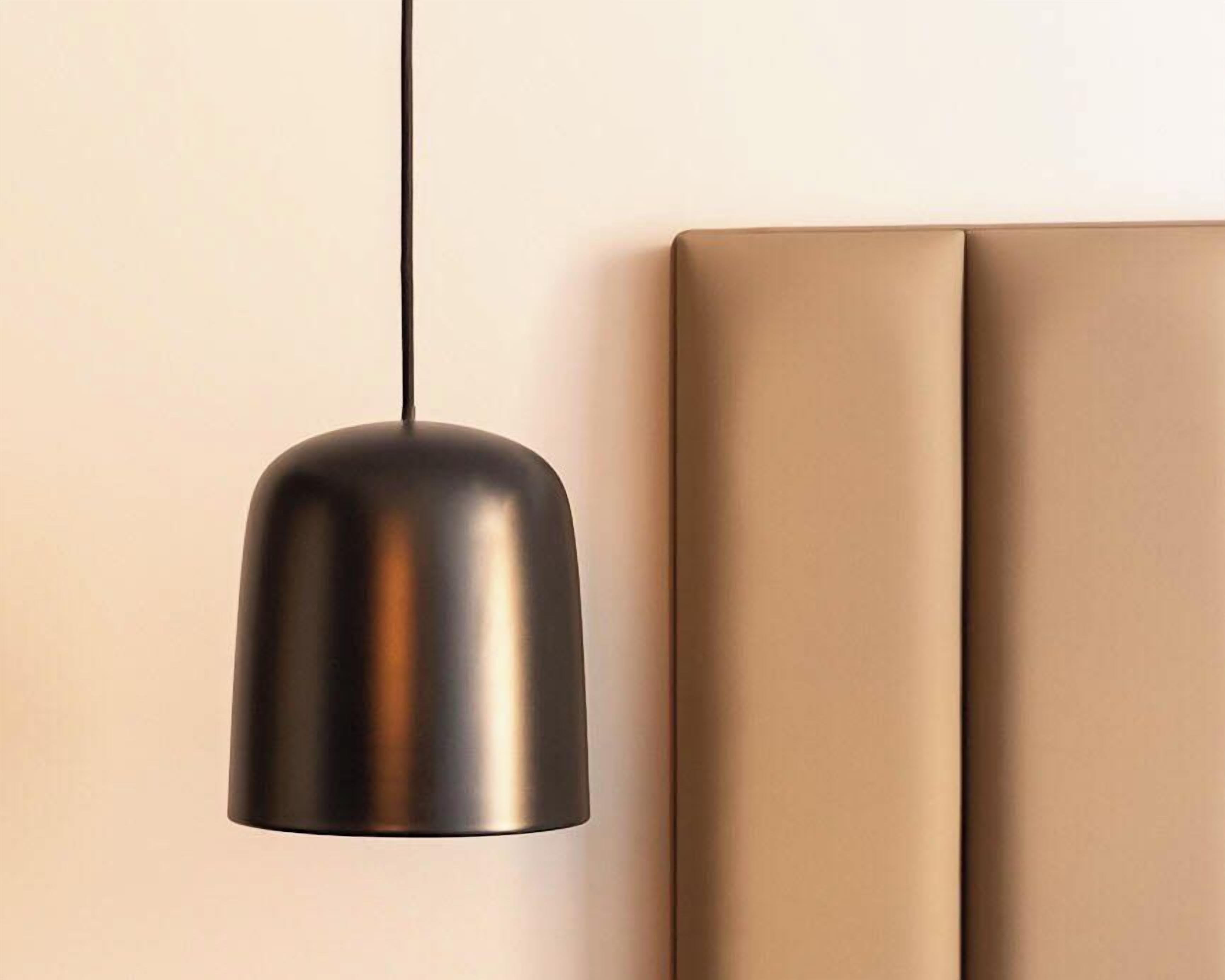 A pendant light fixture with a metallic finish, hanging from a cord.