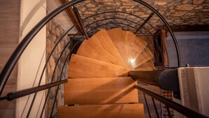 Eine Wendeltreppe mit Holzboden und Metallgeländern führt zu einem Raum mit einer Steinwand und einem Fenster.