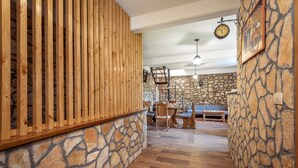 Ein rustikaler Innenraum mit Steinwänden, Holzlatten und einer Treppe zu einem Schlafbereich im oberen Geschoss.