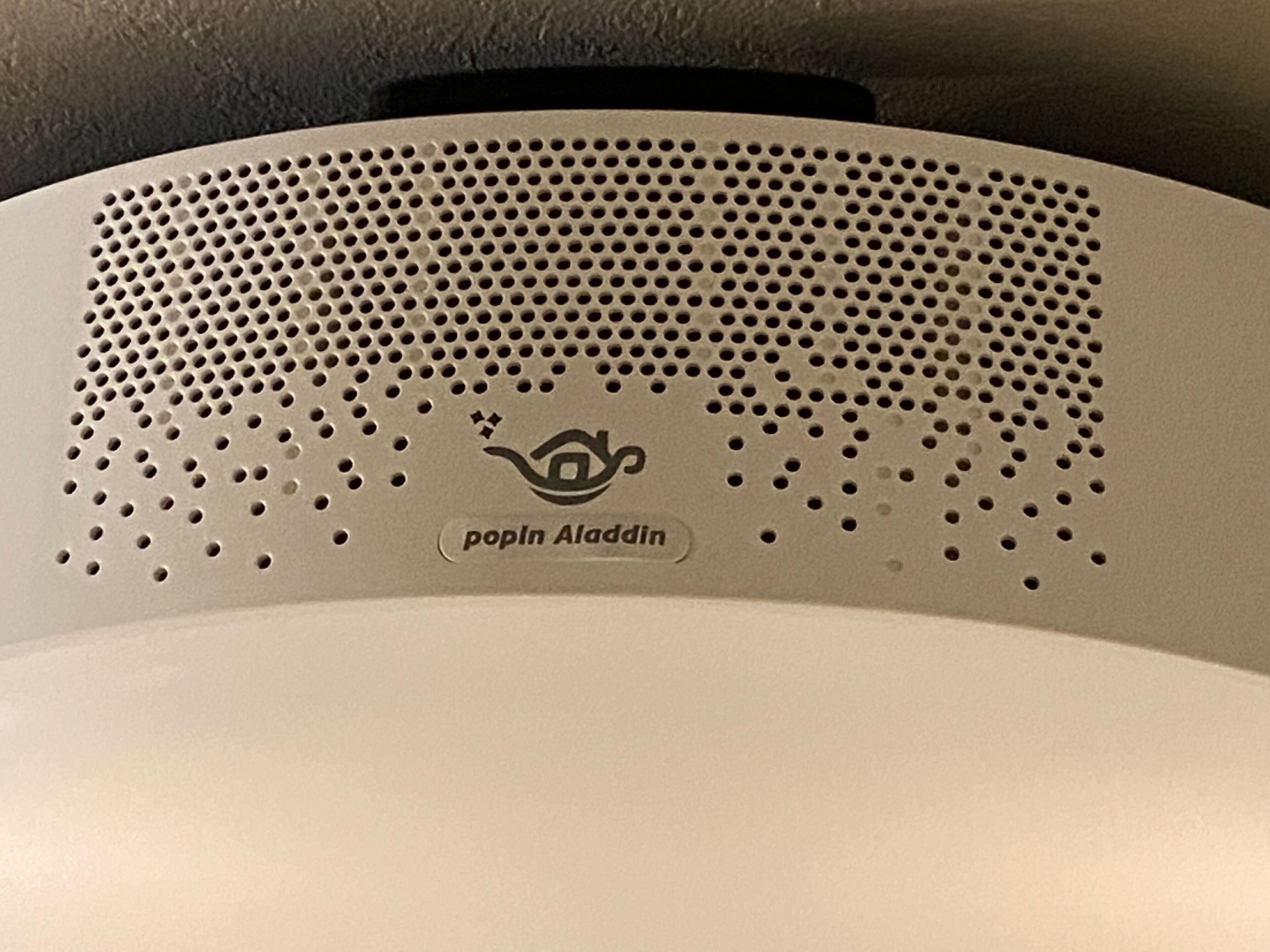 A popin Aladdin speaker with a perforated design and a logo.