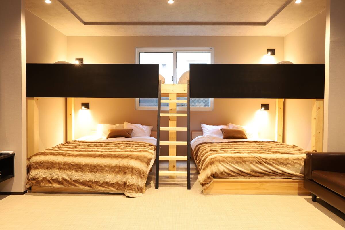 A room with two beds, a ladder, and a window.