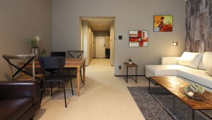 A modern living room with a white sofa, a wooden coffee table, and a dining area with a wooden table and chairs. - UCHI Living Stay AOZORA (Sapporo)