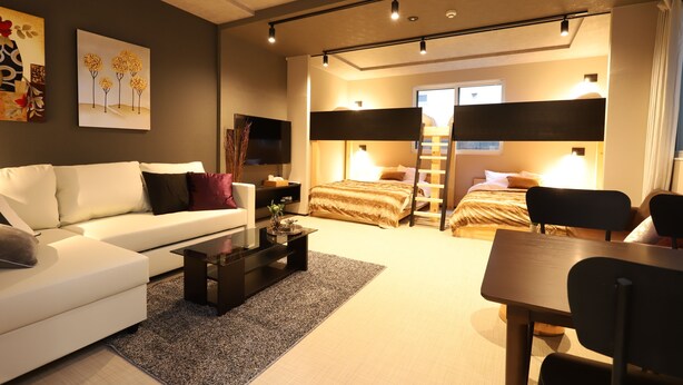 A modern hotel room with a sofa, a small table, a bed, and a desk. - UCHI Living Stay AOZORA (Sapporo)
