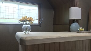 A wooden panel wall, a window with a grid curtain, a vase with yellow flowers, and a lamp on a wooden table. - Guesthouse Sangenya (Shirahama)