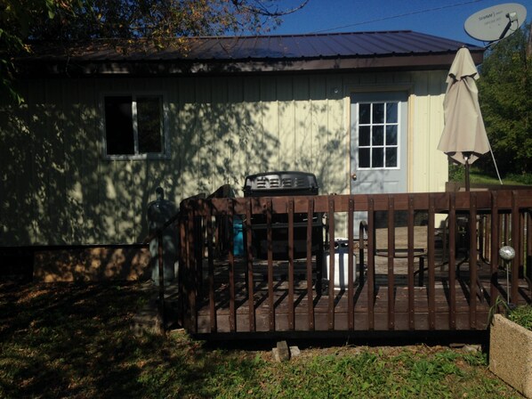 Ein Haus mit Satellitenschüssel, überdachter Terrasse und kleiner Gartenhütte.
