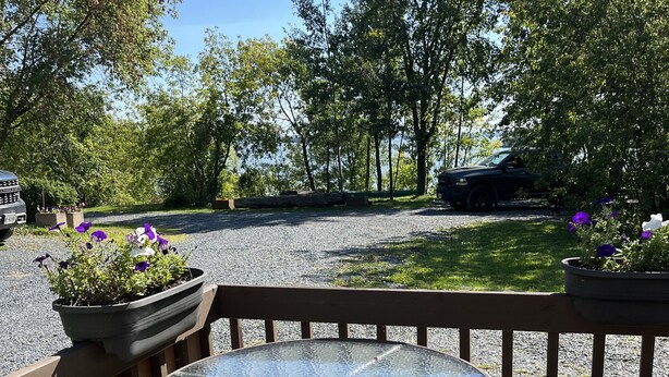 Een ronde glazen tafel met metalen stoelen op een houten terras.