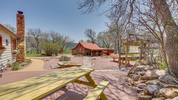 Een rustieke hut met een stenen schoorsteen, een overdekte veranda en een picknicktafel.