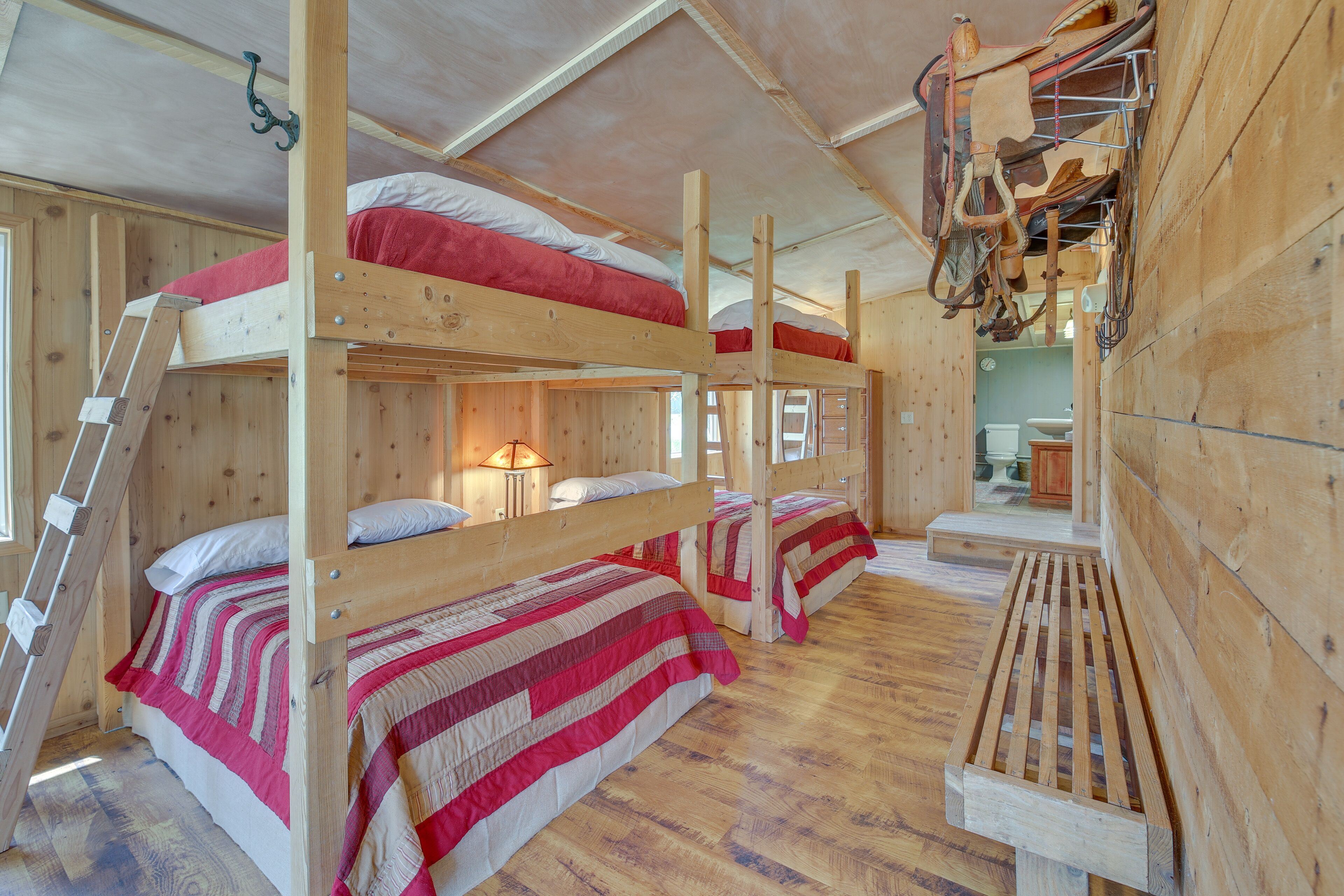 A wooden cabin with bunk beds, a ladder, and a bench.