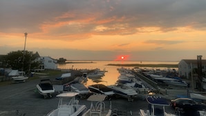 Un puerto deportivo con barcos amarrados, un atardecer al fondo y cielo despejado.