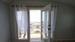 Una habitación con puerta de vidrio corrediza que da a un balcón con vistas a un puerto deportivo y barcos.