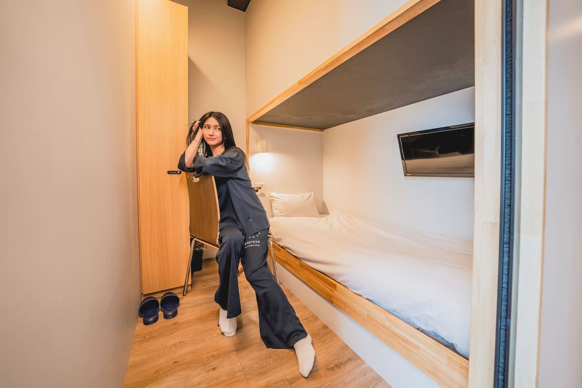 A bunk bed with a wooden headboard and a bedside table with a lamp.