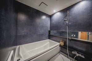 A modern bathroom with a large bathtub, a shower, and a mirror. - Hotel Atarayo Osaka (Osaka)