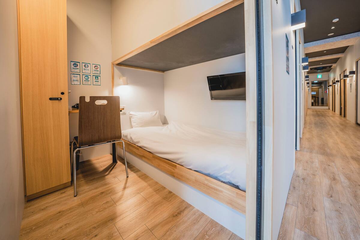 A compact room with a bunk bed, a wooden door, and a small desk.