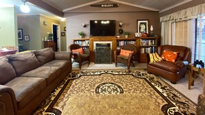 A living room with a brown leather sofa, a patterned rug, and a fireplace. - Located near the historic capitol of the Chickasaw Nation and Blue River (Tishomingo)