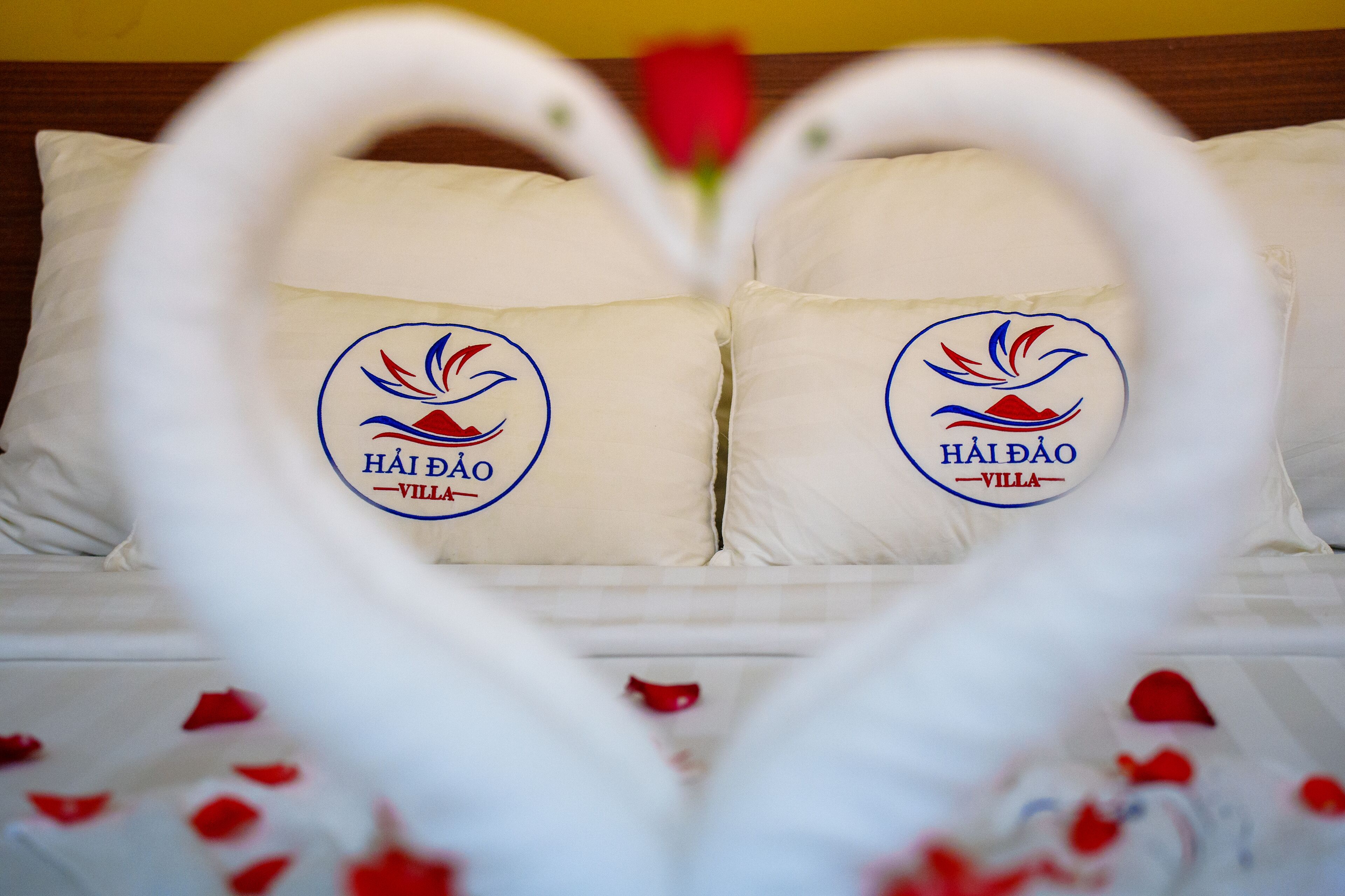 A bed with pillows arranged in a heart shape, each pillow featuring a logo and text.