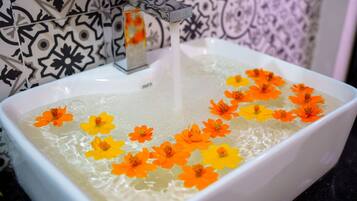 A white rectangular sink with a faucet, filled with water and floating flowers.