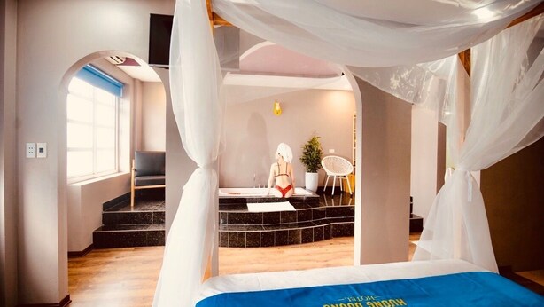 A bedroom with a bed, a bathroom with a bathtub, and a staircase. - Huong Duong Hotel (Hanoi)