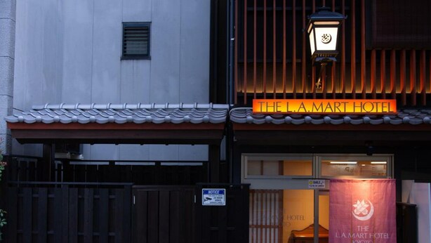 A hotel entrance with a traditional tiled roof, a sign reading "THE L.A. MART HOTEL," and a banner with the hotel's name. - The L.A. Mart Hotel Kyoto (Kyoto)