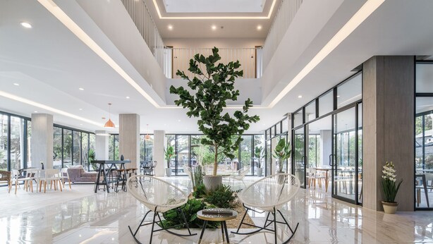 Un hall d’entrée spacieux doté d’un espace salon central, de grandes fenêtres et d’un atrium à plusieurs niveaux.
