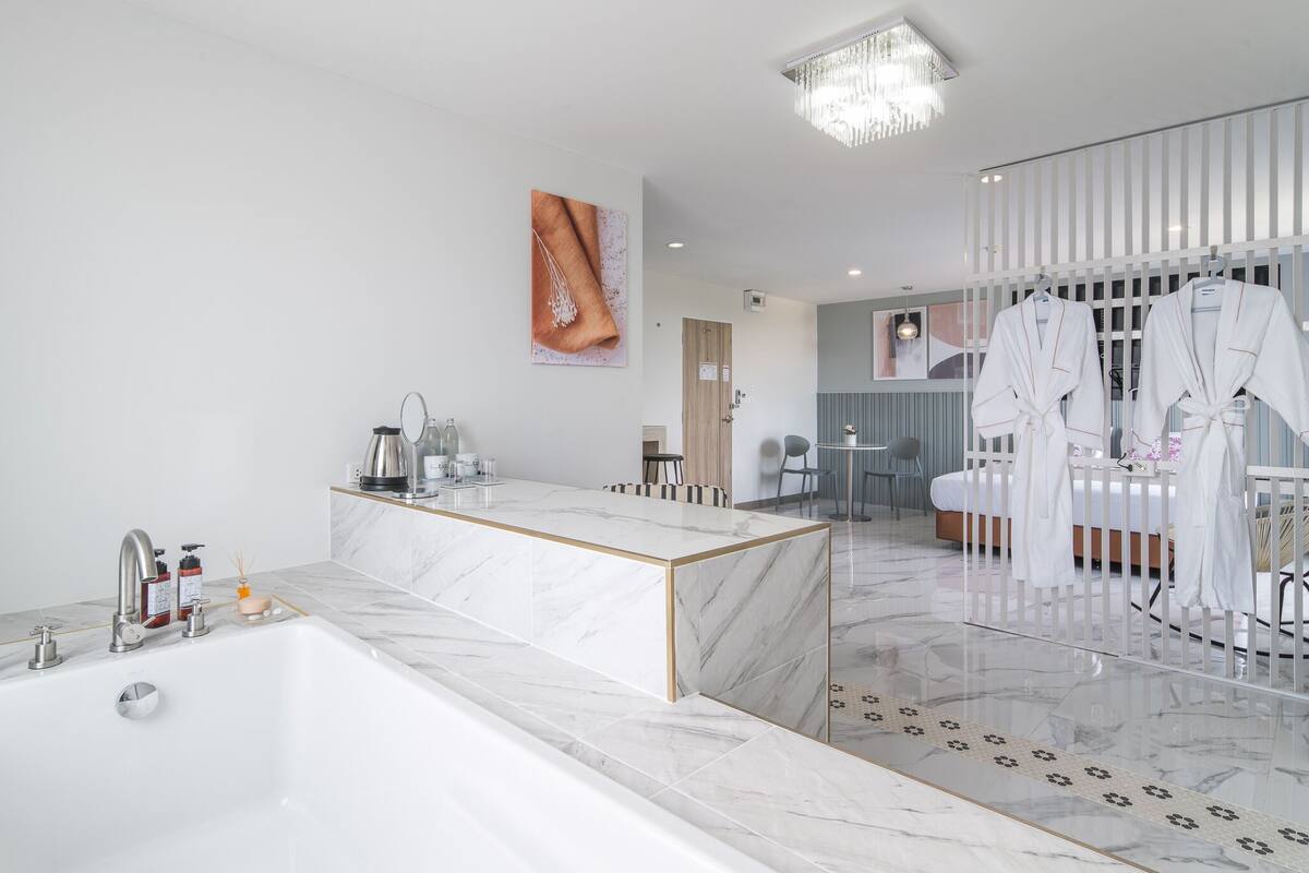 A modern bathroom with a marble sink, a large bathtub, and a glass shower enclosure.