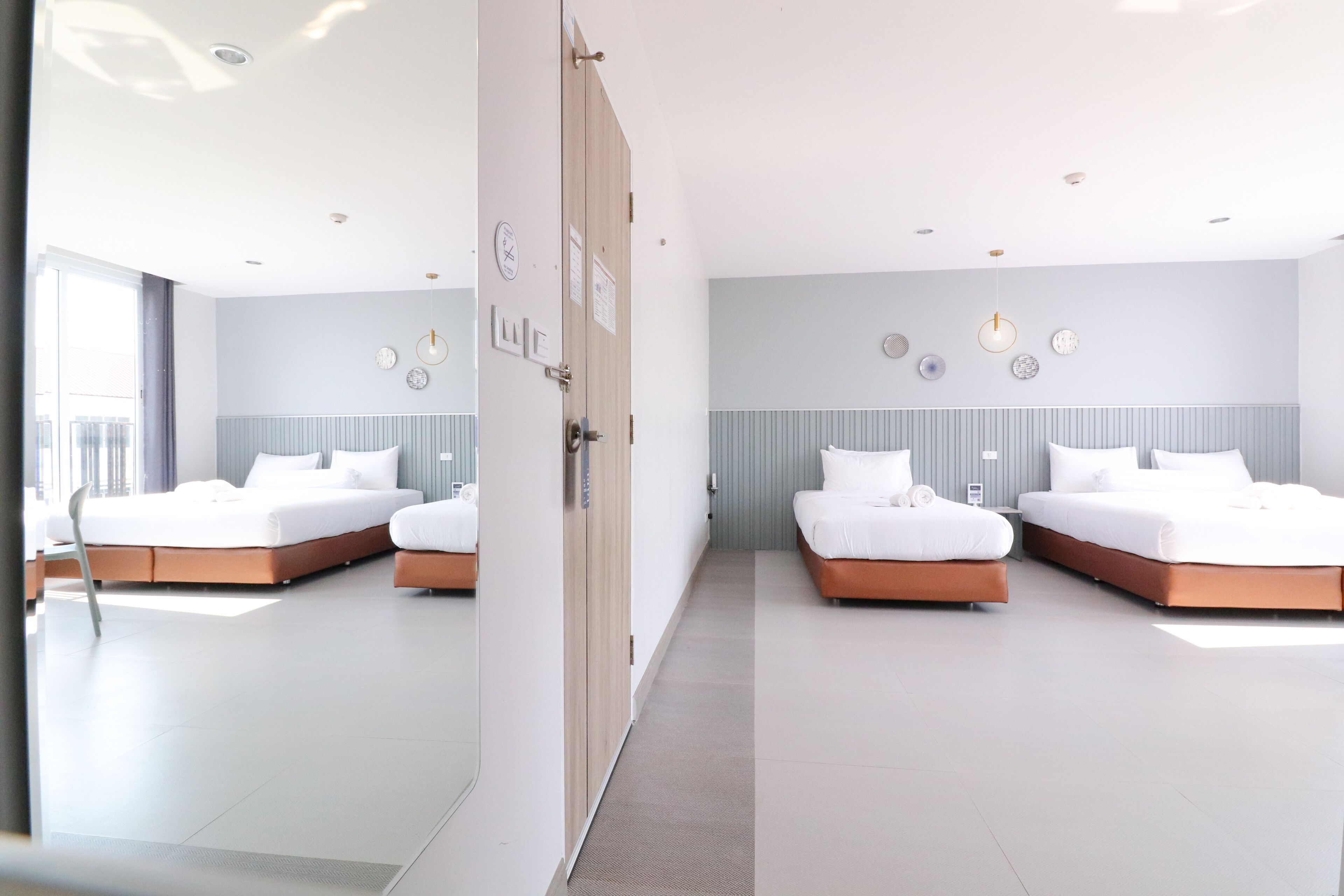 Una habitación de hotel moderna con dos camas, un ventanal grande y una puerta con un reloj.