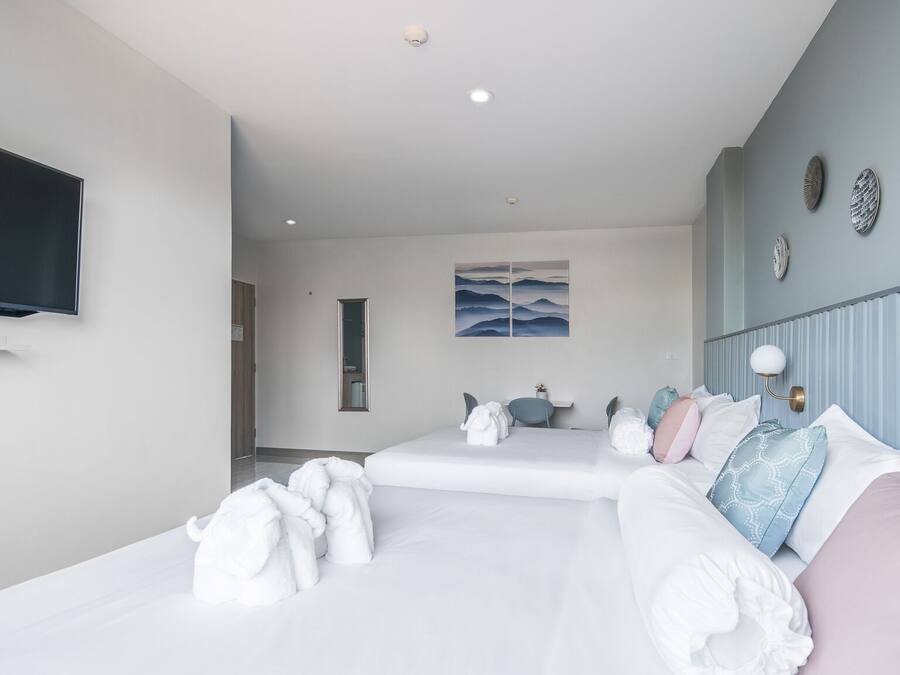 A hotel room with two beds, a flat-screen TV, a painting, and a mirror.