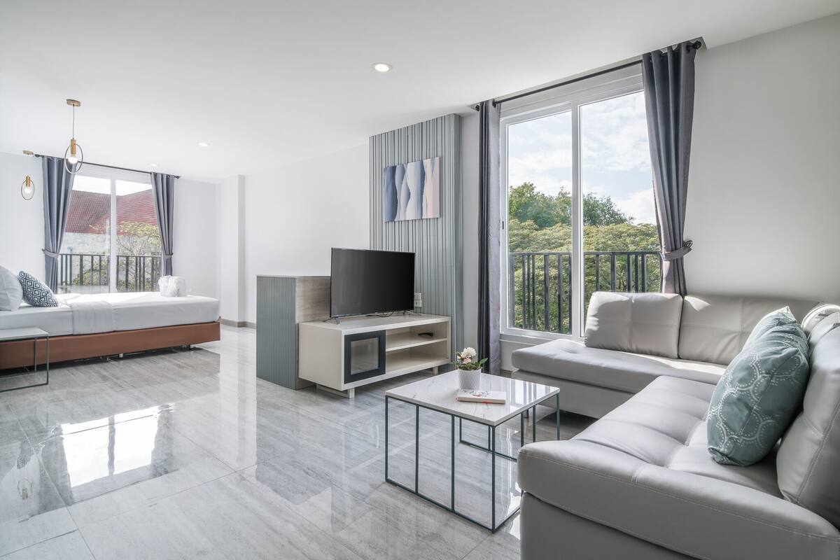 A modern living room with a sofa, a TV, and a balcony.