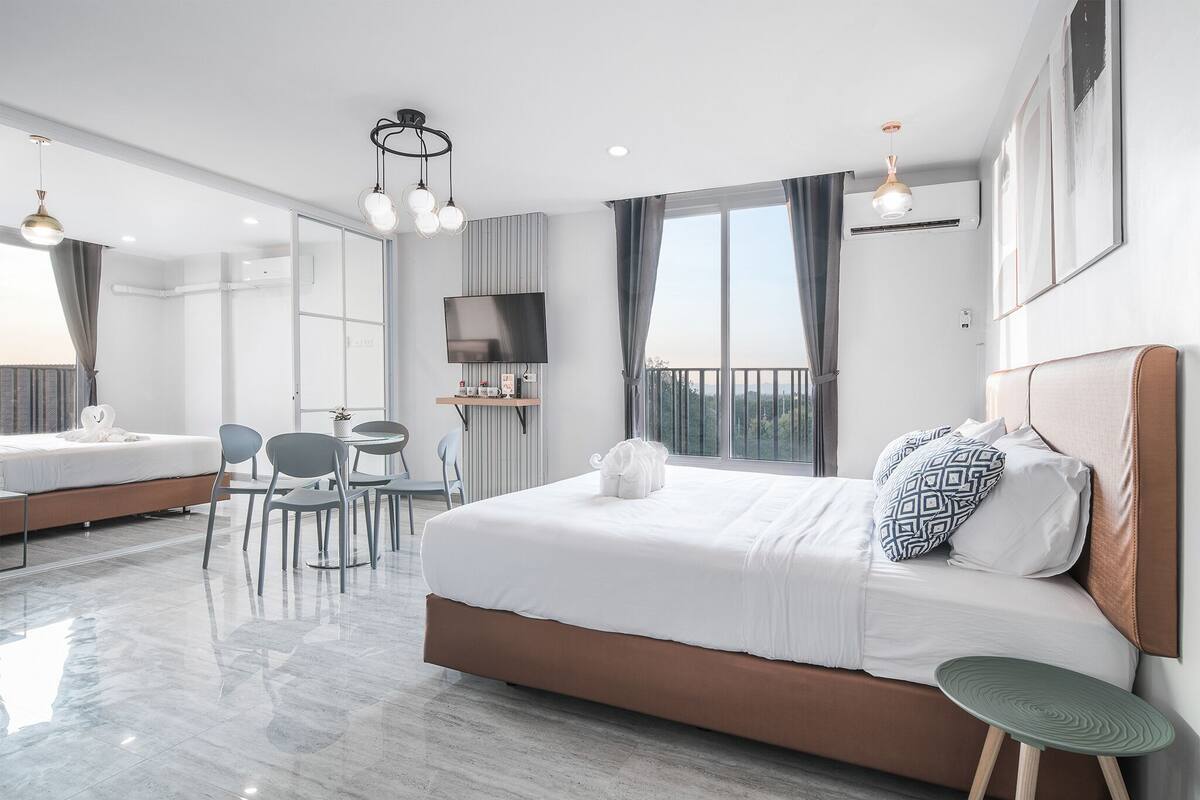 A modern hotel room with a large bed, a desk, and a TV.