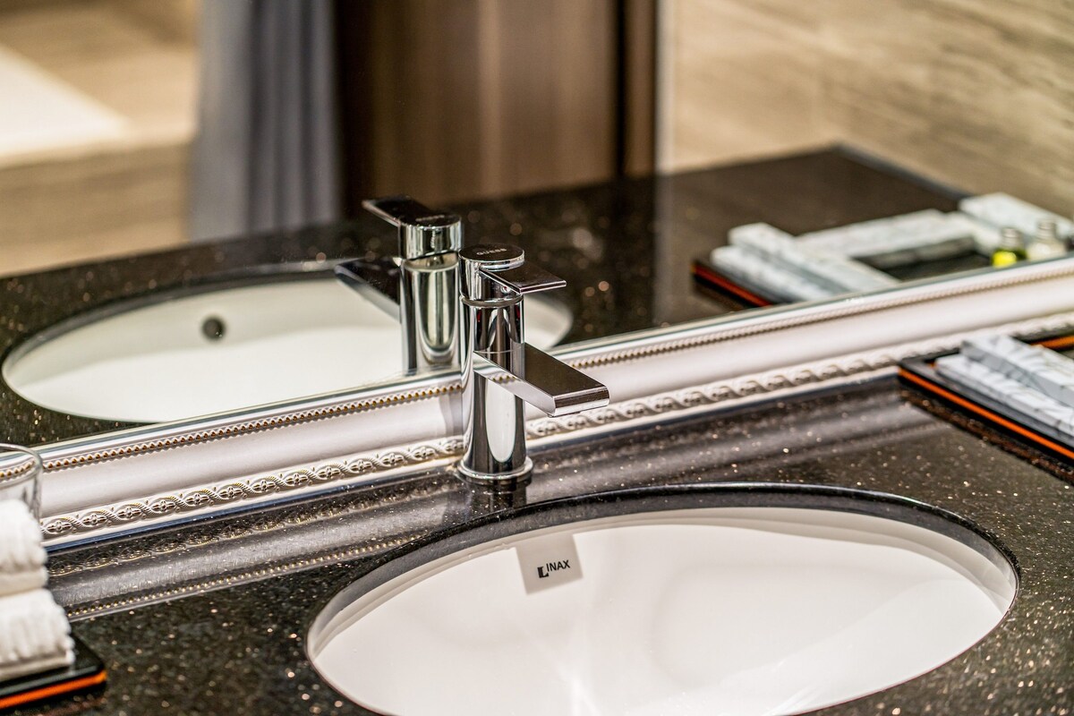 A bathroom sink with a mirror above it, a chrome faucet, and a countertop with a speckled pattern.