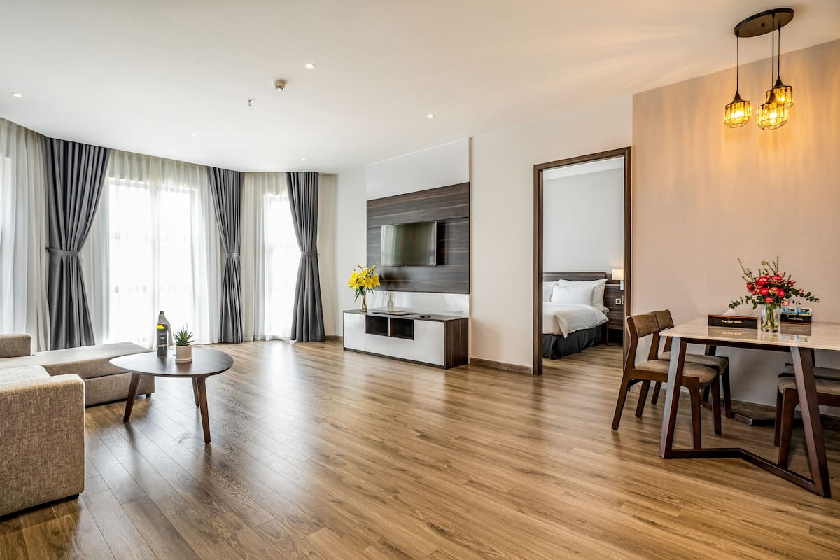 Quarto de hotel moderno com sala de estar, área de refeições e quarto.