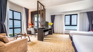 A hotel room with a large bed, a desk with a TV, a sofa, and a view of the sea. - The Cap Hotel (Ho Chi Minh City)
