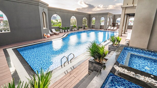 A swimming pool with a tiled deck, lounge chairs, and potted plants. - The Cap Hotel (Ho Chi Minh City)