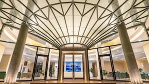 A modern hotel lobby with a glass ceiling, a central staircase, and a reception desk. - The Cap Hotel (Ho Chi Minh City)