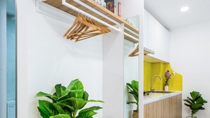 A modern kitchen with a yellow backsplash, wooden shelves, and a built-in bench. - Cozrum Homes Saphera Residence (Ho Chi Minh City)