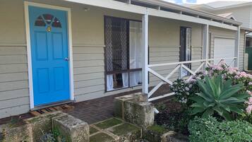 A house with a blue door, a covered porch, and a garden with plants.