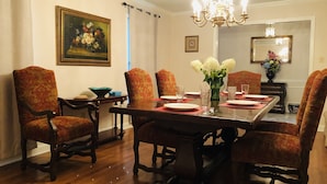 A dining room with a wooden table set for six, surrounded by upholstered chairs.