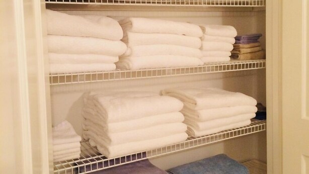 A walk-in closet with multiple shelves holding folded towels in various colors.