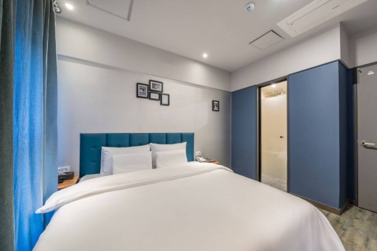 Ein Hotelzimmer mit einem großen Bett, einem Nachttisch, einem Kleiderschrank und einer Tür zu einem Badezimmer.