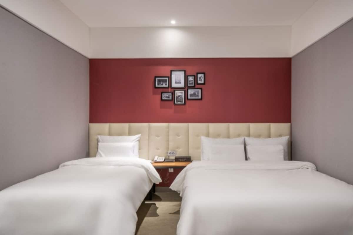 Ein Hotelzimmer mit zwei Betten, einer roten Akzentwand und gerahmten Bildern.