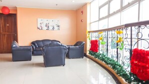 A spacious lobby with a sofa area, a wooden door, and a decorative wall with flowers. - Jy Crown Palace (Cebu City)