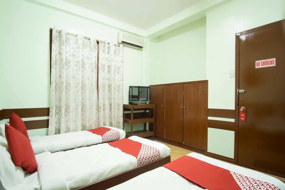 Habitación de hotel con dos camas, televisión, armario y cartel de 'No Fumar'.