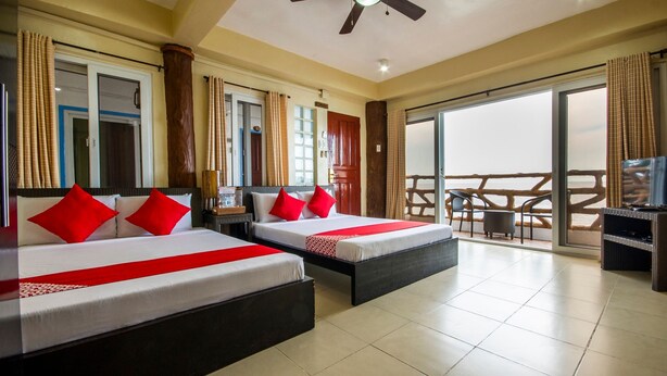 A hotel room with two beds, a balcony with a wooden railing, and a ceiling fan. - Jy Crown Palace (Cebu City)
