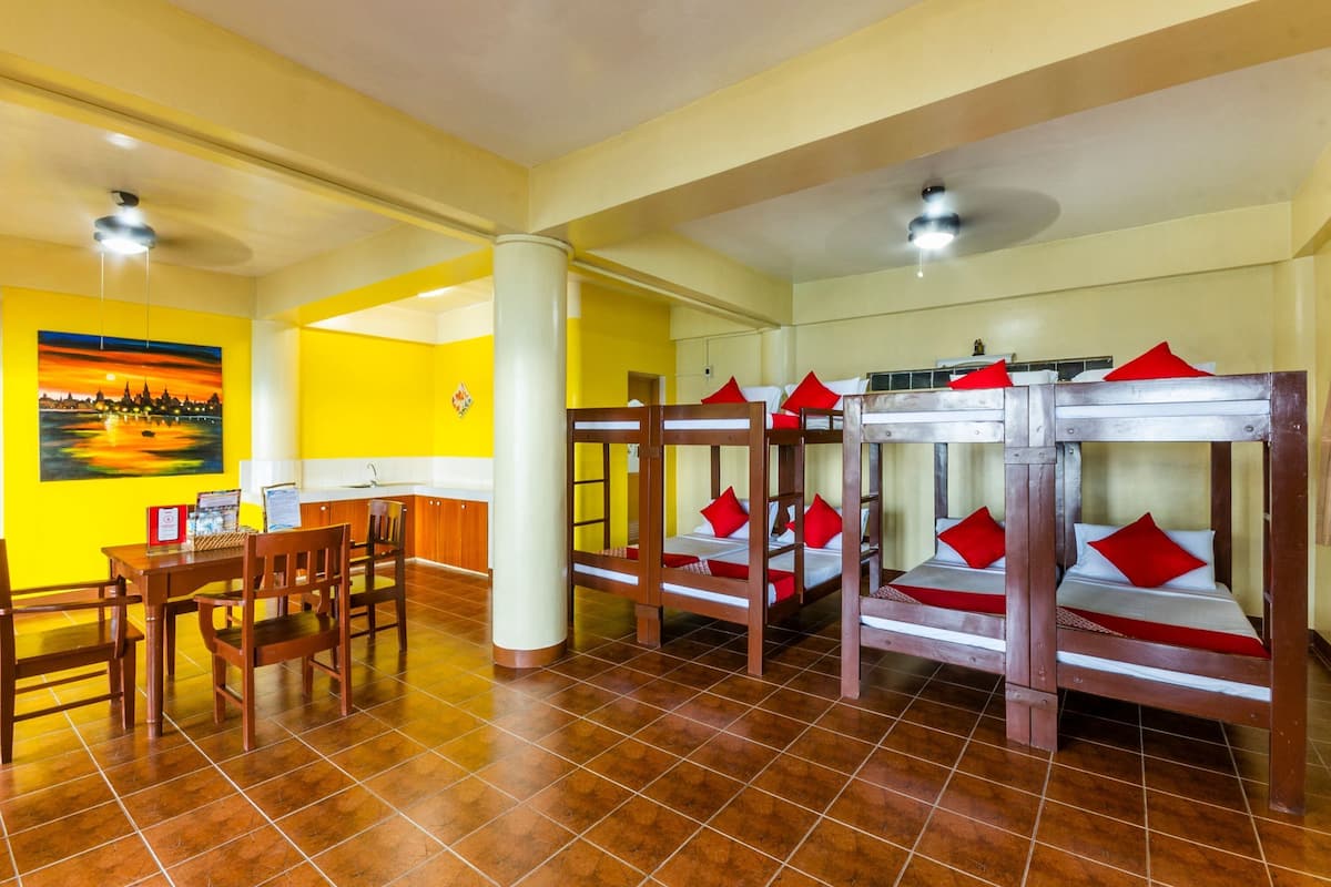 Una habitación con literas, un comedor con sillas y una mesa, y un cuadro en la pared.